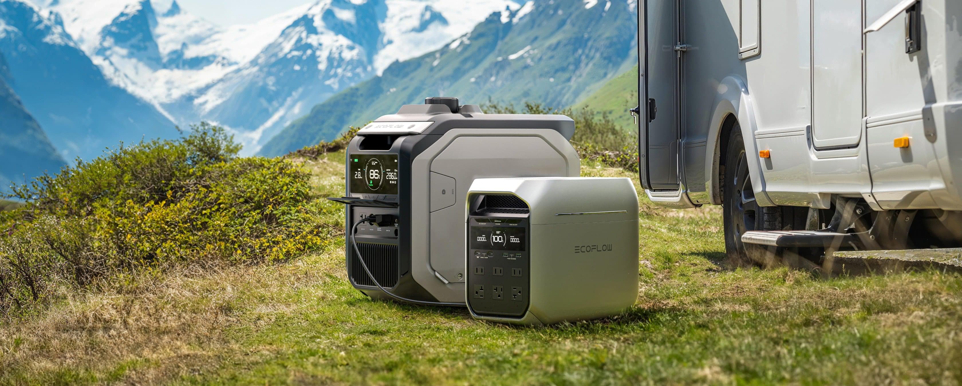 EcoFlow DELTA 3 Plus 1,800W 1,024Wh Plus Portable Solar Power Station Two portable power stations sit on grass beside an RV, with a scenic background of mountains, green hills, and snow-capped peaks under a blue sky.