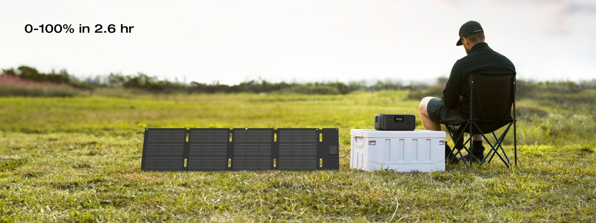 A person relaxes on a folding chair in a grassy field next to a white cooler and the EcoFlow RIVER 3 300W 245Wh Portable Solar Power Station, highlighting fast 0-100% charging in 2.6 hr—ideal for outdoor power needs.