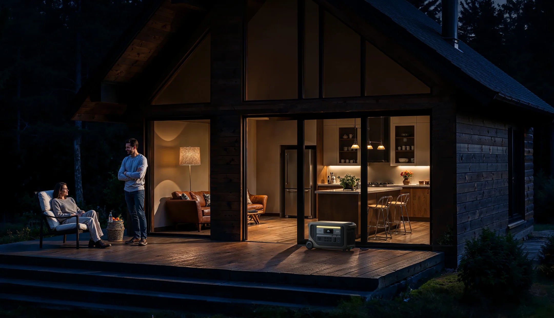 Anker SOLIX F3000 Portable Power Station + BP3000 Expansion Battery | 3,600W Power Output and 6,144Wh Battery Storage A man and woman relax on the illuminated porch of a cozy cabin at night, powered by the Anker SOLIX F3000 Portable Power Station (3,600W output, 3,072Wh storage), surrounded by trees.